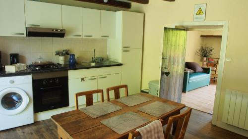 a kitchen with a wooden table and a kitchen with a washer at Les 3 pruniers in Cieux