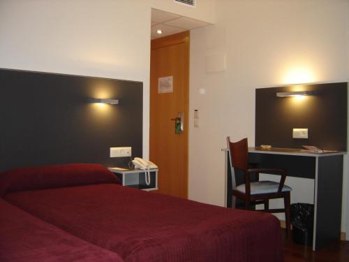 a hotel room with a red bed and a desk at Hotel Alfinden in Puebla de Alfindén