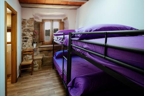 two bunk beds in a room with purple sheets at L'alberg la rectoria de la Torra in La Baronia de Rialb