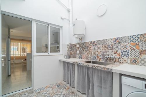 a white kitchen with a sink and a mirror at Les Villetes in Moncófar
