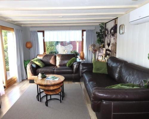 a living room with a leather couch and a table at Veluwe Park Reewold Chalet Eclipse in Putten
