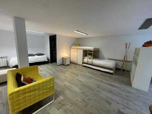 a living room with a yellow couch and a bed at Villa Bosque Albite in Llanera