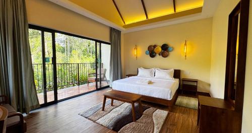 a bedroom with a white bed and a balcony at Flower Valley Plantation Homestay in Munnar