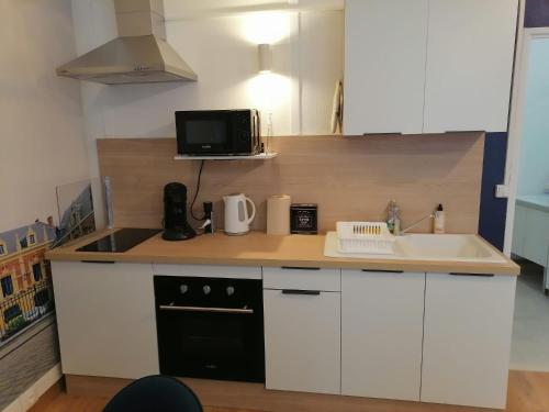 a kitchen with white cabinets and a black appliance at Le Coeur du Beffroi in Douai
