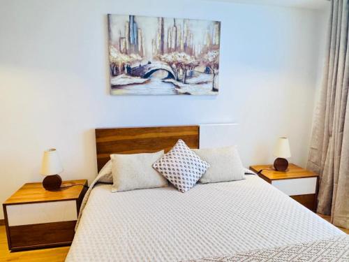 a bedroom with a bed with two night stands and a painting on the wall at Bela Vista Studio in Ponta Delgada