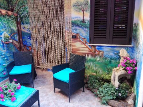 two chairs and a table in front of a mural at B&B Oasi Tepilora in Bitti
