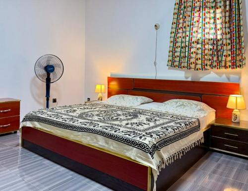 a bedroom with a bed and a fan at Residence MiMi Alouar Ziguinchor in Tilel