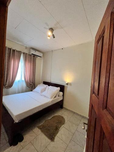 ein kleines Schlafzimmer mit einem Bett und einem Fenster in der Unterkunft Nouji in Douala
