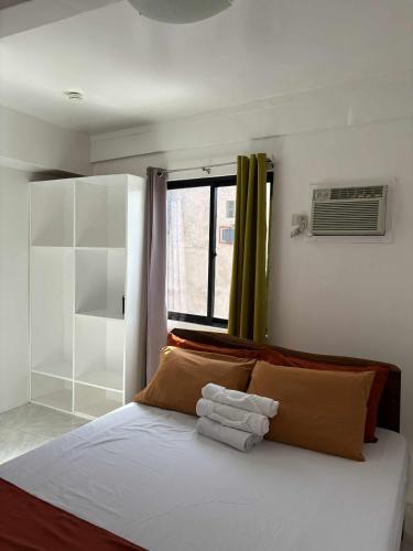 ein Schlafzimmer mit einem Bett mit Kissen und einem Fenster in der Unterkunft Leonardo Hostel in Anda