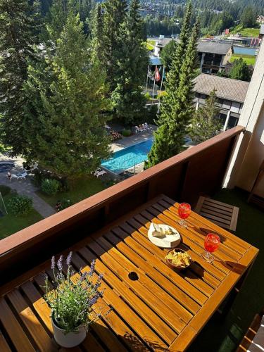 a wooden table on a balcony with a view of a pool at HappyLaax - Panoramic Penthouse - Pool, Sauna & Private Parking in Laax