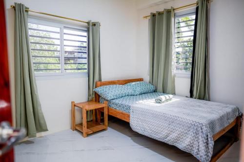 a bedroom with two beds and a table and windows at Jannish Transient House in Masbate