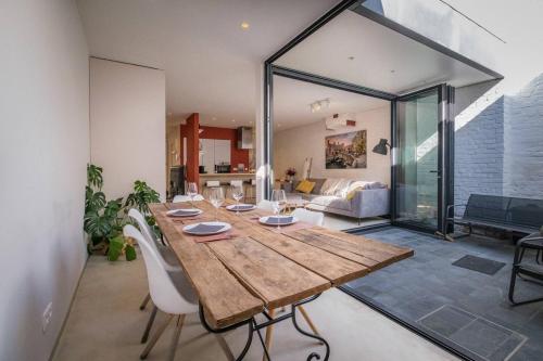 a dining room with a wooden table and a living room at Maison Bonheur in Bruges