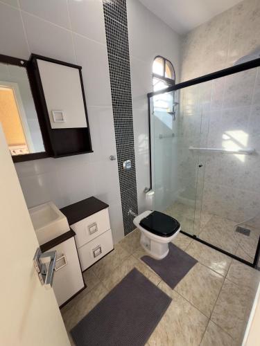 a bathroom with a toilet and a glass shower at Casa Brisa do Mar in Governador Celso Ramos