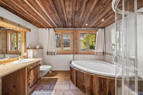 a bathroom with a wooden ceiling and a tub and a toilet at Chalet Chavanette - Beautiful 7 bedrooms Chalet in Champéry