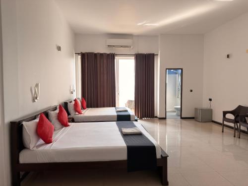 a bedroom with two beds with red pillows at Atarah Beach Hotel in Negombo