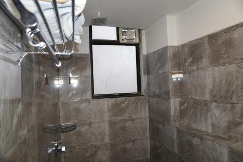 a bathroom with a shower with a mirror and a window at Hotel Nilax in Jaipur