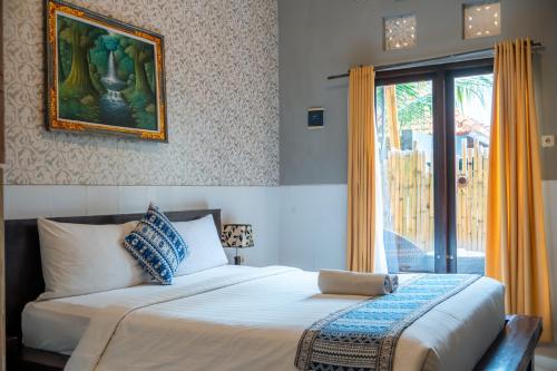 a bedroom with a bed with a picture on the wall at Wana Kubu Homestay in Kuta