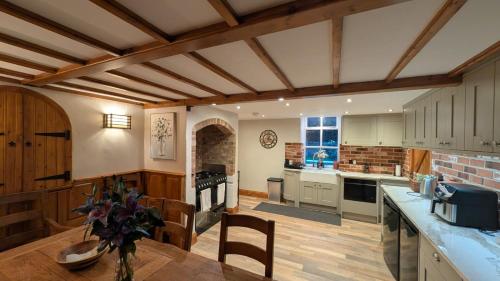a kitchen with white cabinets and a table with a vase of flowers at Bradford Canal Pump House, Shipley near Saltaire in Shipley