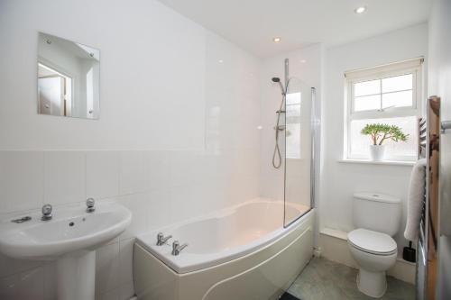 a white bathroom with a tub and a sink and a toilet at Sawadee Apartments in Warwick