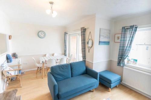 a living room with a blue chair and a table at Lansdowne - Charmouth Sea Retreat in Bridport