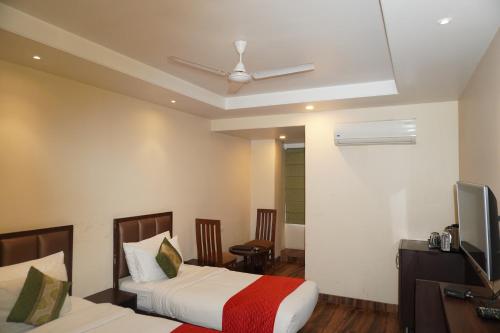 a bedroom with two beds and a television in it at Hotel Nilax in Jaipur