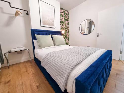 a bedroom with a blue and white bed with a mirror at Modern two bedroom flat with private garden in London