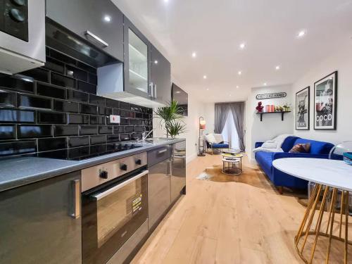 a kitchen and living room with a blue couch at Modern two bedroom flat with private garden in London