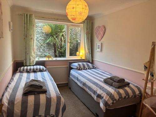 two beds in a room with a window at Lansdowne - Charmouth Sea Retreat in Bridport
