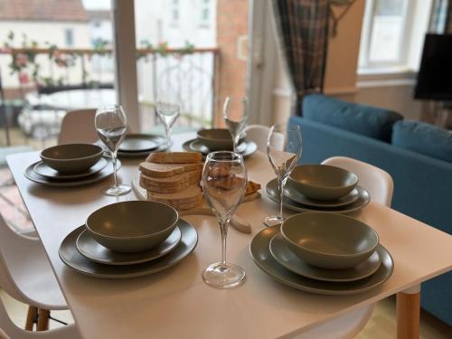 a table with plates and wine glasses on it at Lansdowne - Charmouth Sea Retreat in Bridport