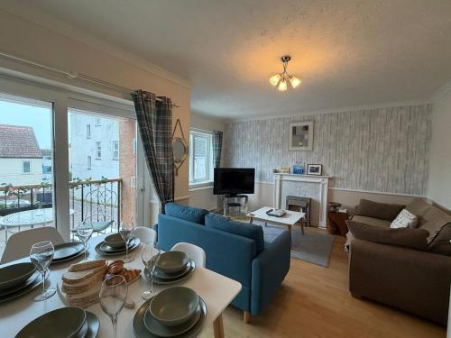 a living room with a blue couch and a table at Lansdowne - Charmouth Sea Retreat in Bridport