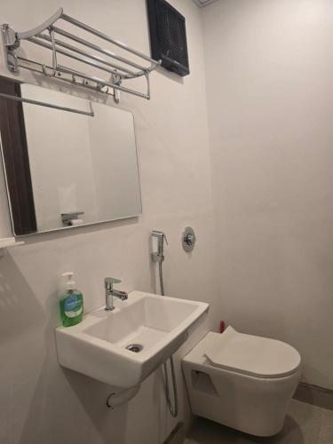 a white bathroom with a sink and a toilet at Prafulla Homestay in Kārwār