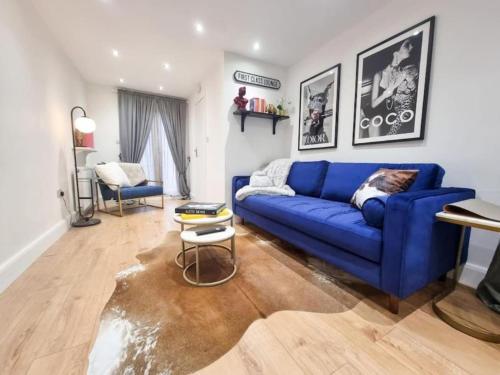 a living room with a blue couch and a table at Modern two bedroom flat with private garden in London