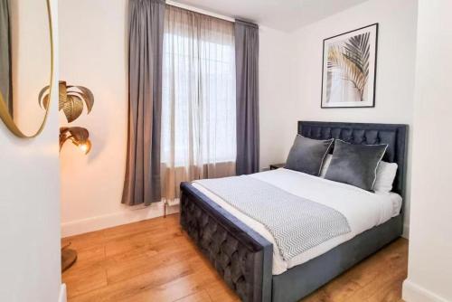 a bedroom with a bed and a window at Modern two bedroom flat with private garden in London