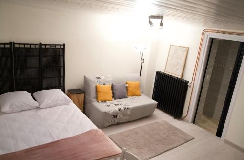 a bedroom with a bed and a couch with orange pillows at Studio - Free Parking - Netflix - Wi-Fi in Brive-la-Gaillarde