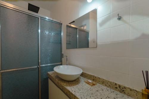 a bathroom with a sink and a glass shower at Espaçoso e Confortável Próximo da UEM - EL08 in Maringá