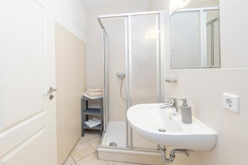 ein weißes Badezimmer mit Waschbecken und Dusche in der Unterkunft Elbkajüte in Grünendeich