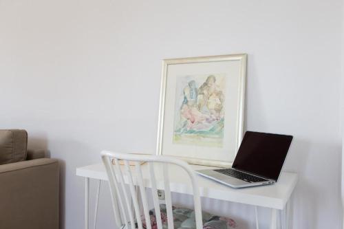 a laptop computer sitting on a white desk with a chair at Apartments Roža in Medulin
