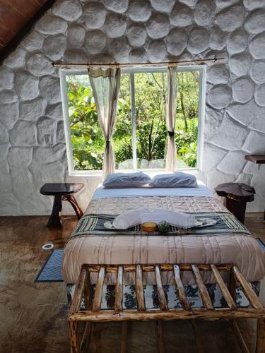 a bed in a room with a large window at Cacao Glamping Lodge & Experience in Cotundo