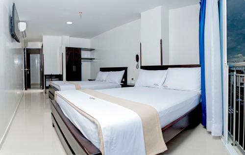a bedroom with two beds and a balcony at Hotel Isla Mayor in Bucaramanga