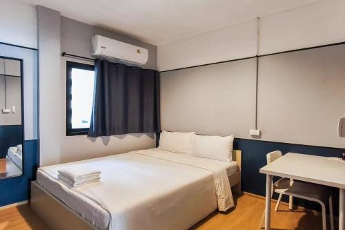 a bedroom with a bed with a desk and a window at Borbaboom Phuket Poshtel & Hostel in Phuket