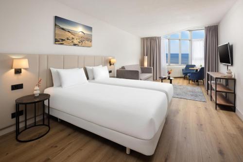 a large white bed in a hotel room at NH Zandvoort Hotel in Zandvoort