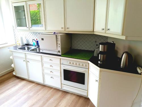a kitchen with white cabinets and a sink and a microwave at Ferienwohnung 1 Christiansdorf Freiberg in Freiberg