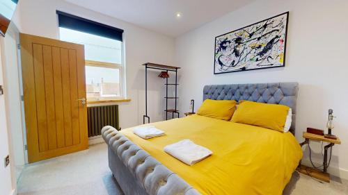 a bedroom with a large bed with yellow sheets at Stylish 2 Bed Apt, 2 Minute Walk From The Beach. in Sheringham