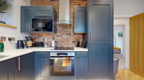 a kitchen with blue cabinets and a stove at Stylish 2 Bed Apt, 2 Minute Walk From The Beach. in Sheringham