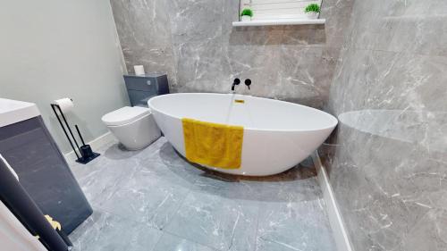 a bathroom with a white tub and a toilet at Stylish 2 Bed Apt, 2 Minute Walk From The Beach. in Sheringham