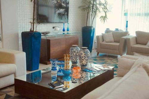 a living room with blue vases on a glass table at Hotel Village in Garanhuns