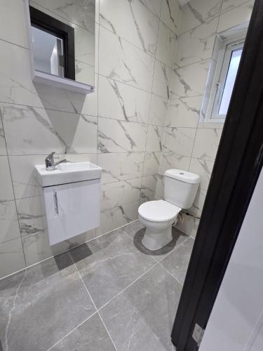 a white bathroom with a toilet and a sink at 1066 Apart Hotel in Hastings