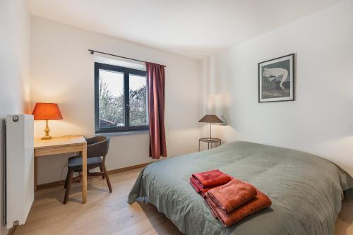 a bedroom with a bed and a desk and a window at Butte du Lion in Genappe