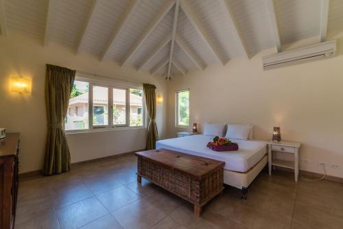 a bedroom with a large white bed and a table at Villa Kas ku Playa 55 - Coral Estate in Willibrordus