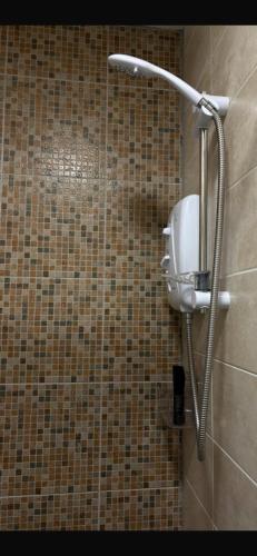 a shower in a bathroom with a tile wall at Half Pint Cottage in Draperstown